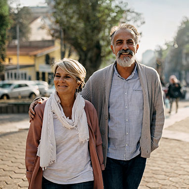 Elderly couple smiling while walking down street